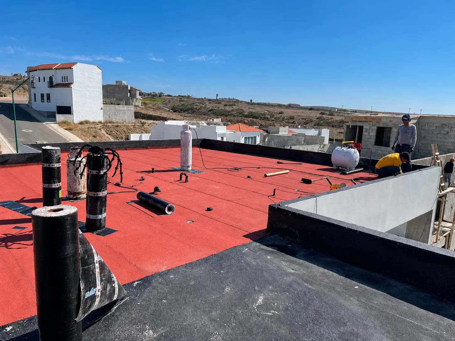 Pretil impermeabilizado y rollos de prefabricado en obra residencial